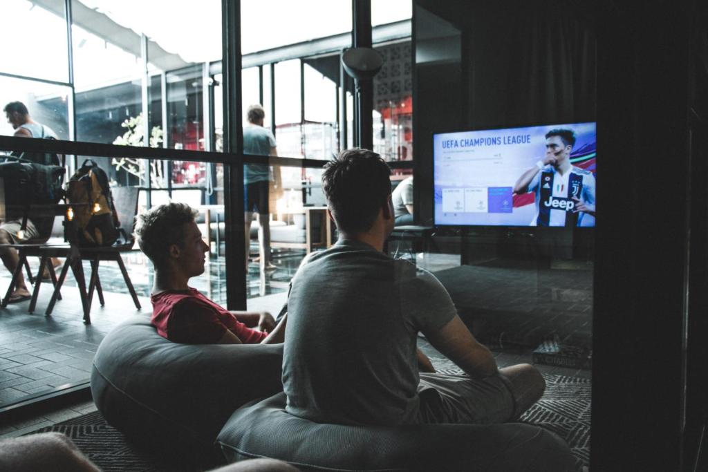 two people sitting on a couch watching a tv at Luk Hostel in Bangkok