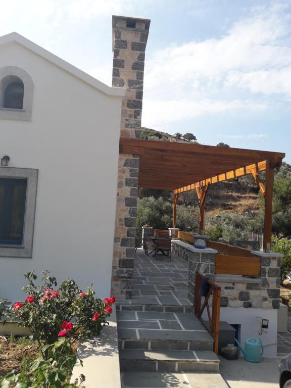 a patio with a wooden pergola next to a white building at Villa Polymnia in Emborios