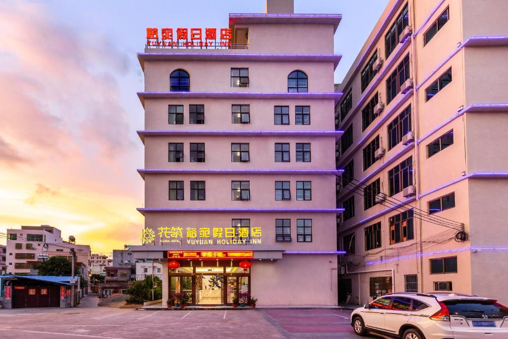 Ein hohes weißes Gebäude mit einem Schild drauf. in der Unterkunft Floral Hotel · Yu Wan Holiday Lingshui in Lingshui