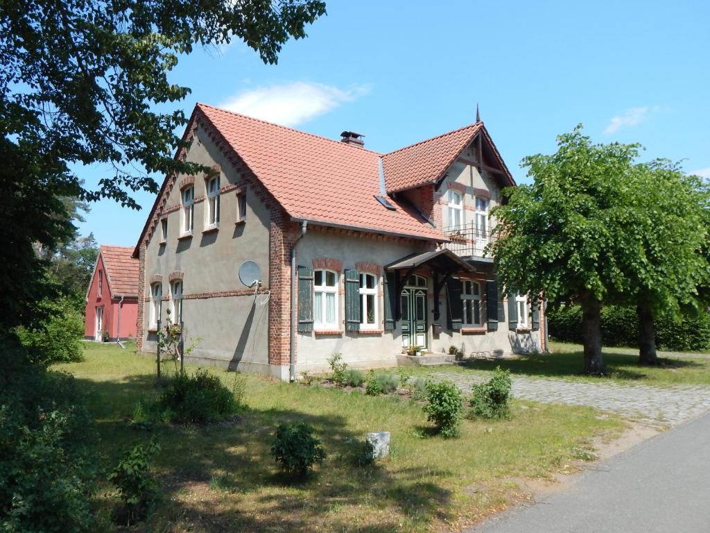 una casa con techo rojo y un árbol en Ferienhaus am Wald mit Klavier, Holzofen, Sauna, en Alt Jabel