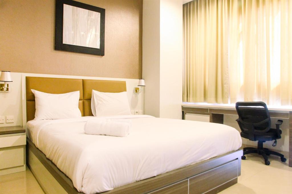 a bedroom with a bed and a desk and a chair at Deluxe and Modern Studio M Gold Tower Apartment By Travelio in Bekasi