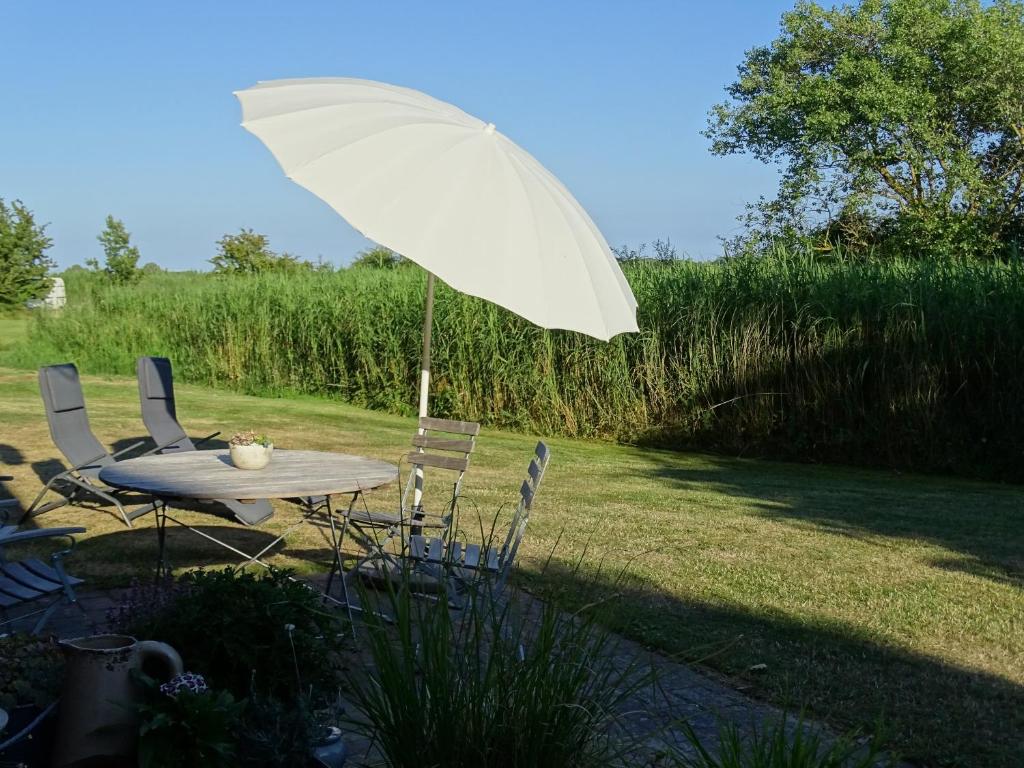 uma mesa e cadeiras com um guarda-sol num quintal em Der Ferienhof am Meer em Fehmarn