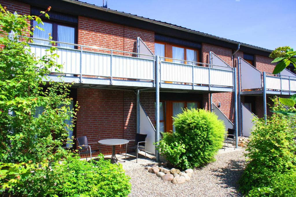 a building with a balcony and a table in a yard at Ferienwohnungen Gaebert in Kellenhusen