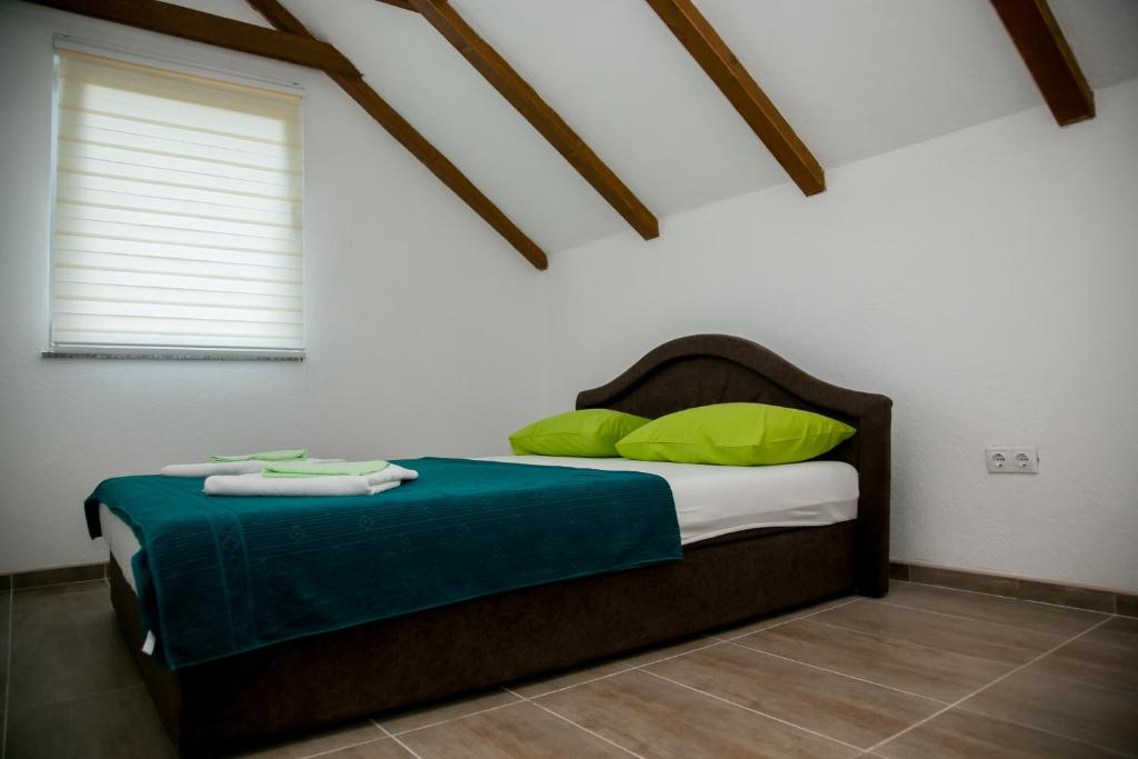 a bedroom with a bed with green pillows and a window at Nektar Park Villa Sara in Bihać