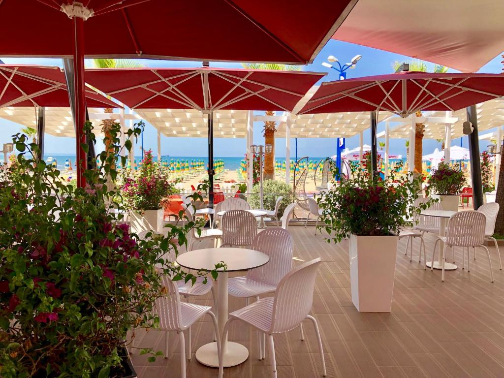 a patio with tables and chairs and red umbrellas at Hotel Virginia in Durrës