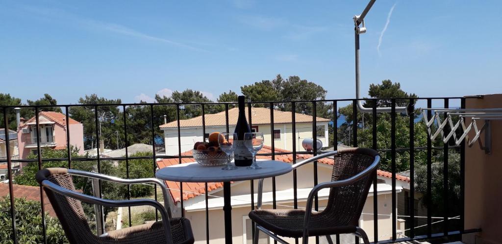 a table with two chairs and a bottle of wine on a balcony at Alexander Apartments in Skala