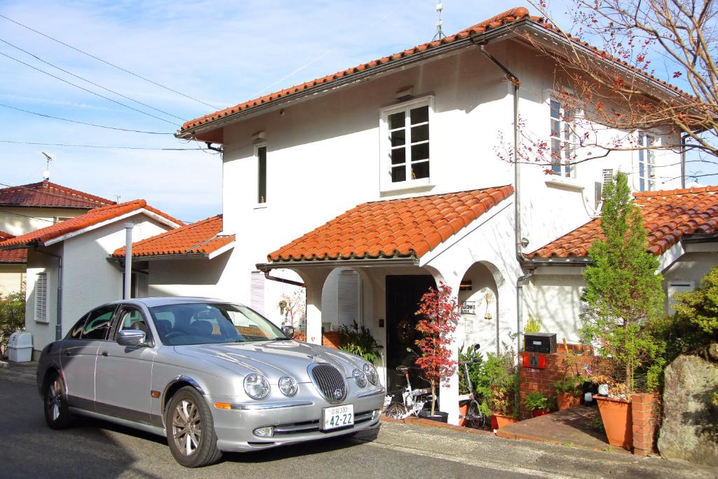 un coche plateado estacionado frente a una casa blanca en Jonni`s Place, en Sakamoto