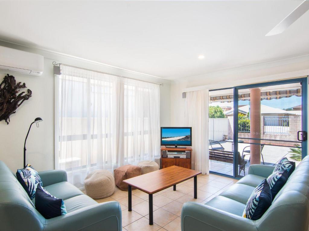 a living room with a couch and a table and a television at 1 54 Parkes Street in Tuncurry