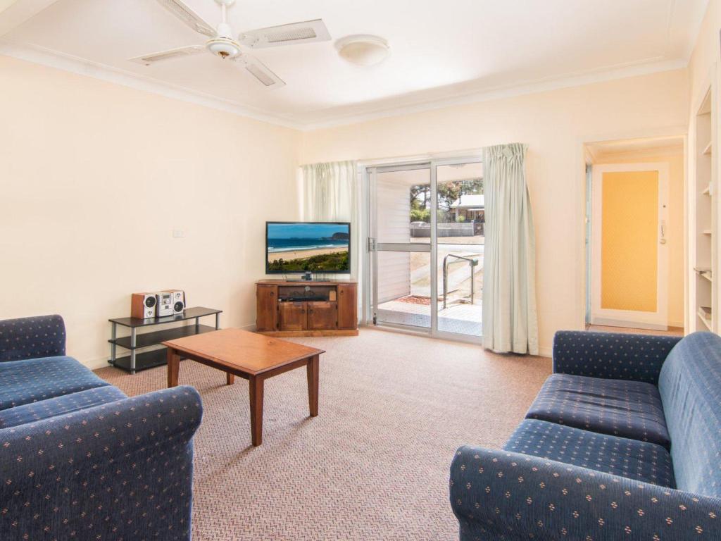 a living room with two blue couches and a tv at 11 Peel Street in Tuncurry