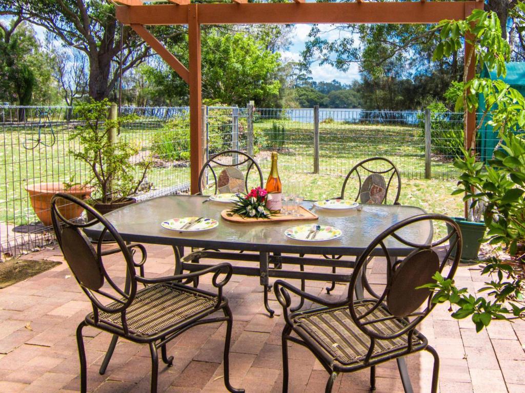 a patio table with four chairs and a bottle of wine at 11 Bay Street - waterfront holiday in Tuncurry