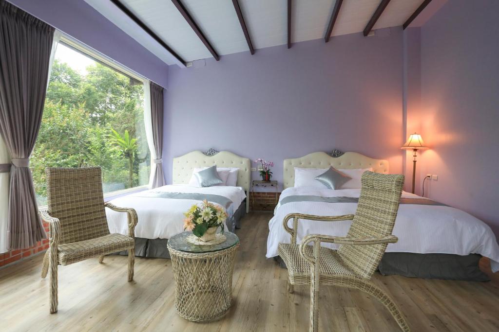 a purple bedroom with two beds and two chairs at Zhen Shan Zhuang B&amp;B in Yuanshan