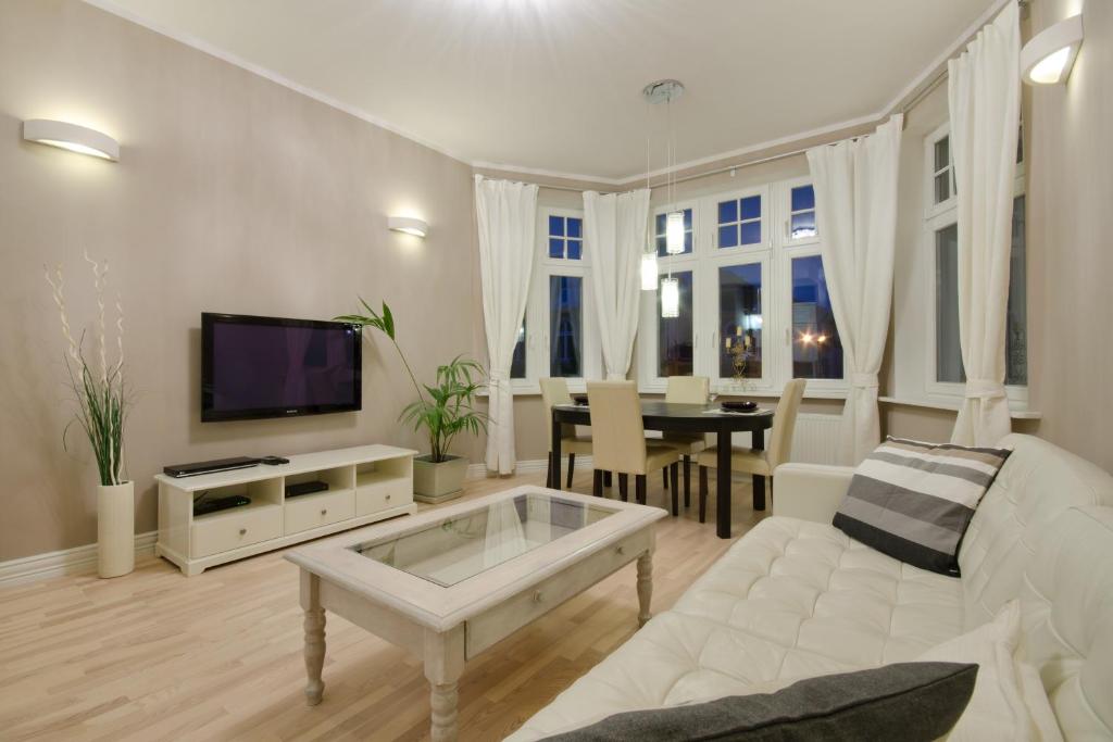 a living room with a white couch and a tv at Apartament Molo in Sopot