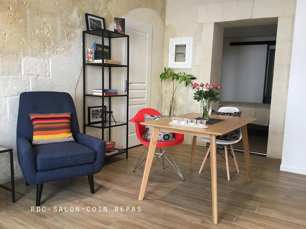 a living room with a table and a blue chair and a table and a chair at Appartement Arles Centre Historique in Arles