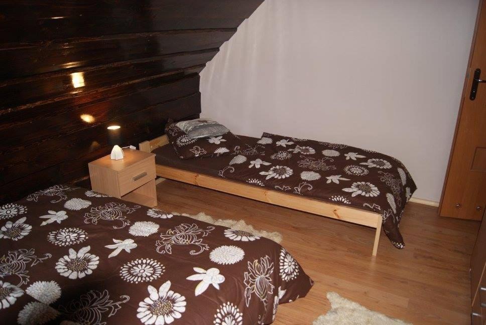 a bedroom with two beds and a wooden wall at Domek Całoroczny OSTOJA in Istebna