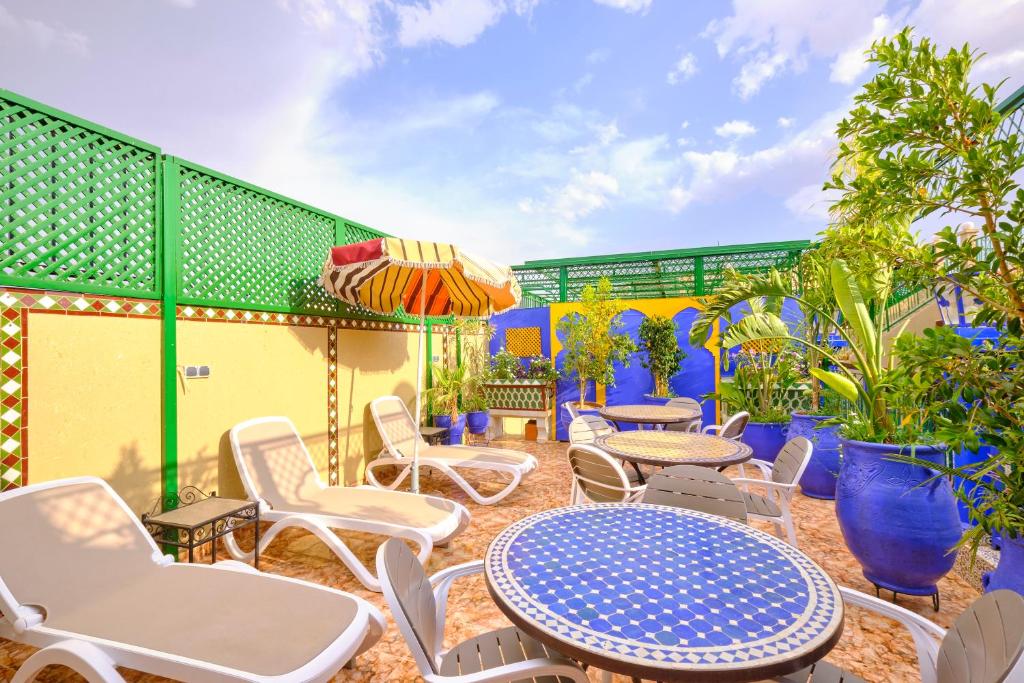 a patio with chairs and tables and an umbrella at Hotel Central Palace in Marrakech