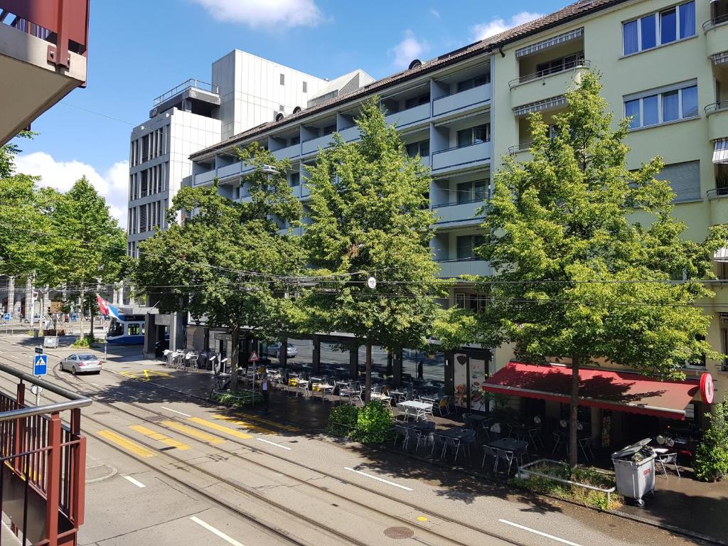 a building with trees and a train in front of it at Doubleroom close to lake in Citycenter in Zürich