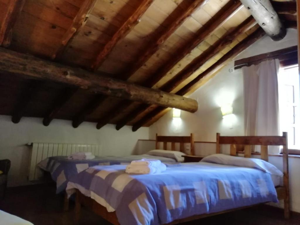 1 dormitorio con 2 camas en una habitación con techos de madera en Casa Rural La Pontezuela Arriba, en Navarredonda de Gredos