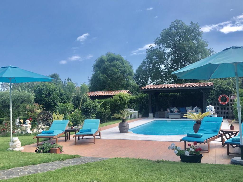 a swimming pool with blue chairs and umbrellas at Lugar Meluerda in Meluerda