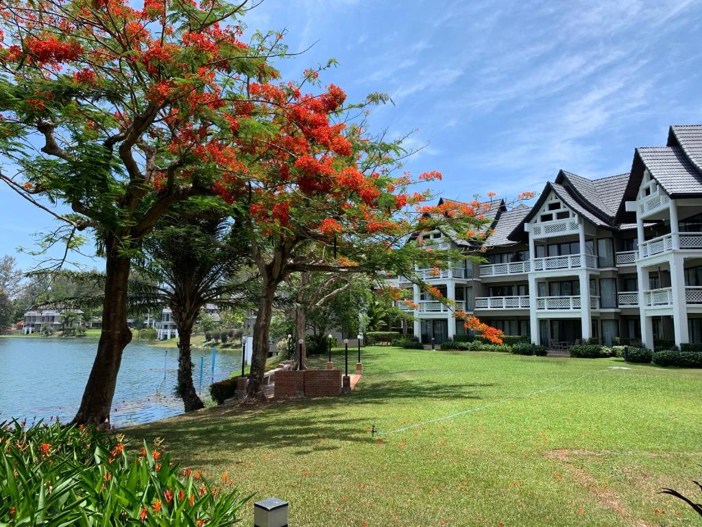 duży budynek apartamentowy z drzewem z czerwonymi kwiatami w obiekcie Allamanda Apartments by Laguna Phuket w mieście Bang Tao Beach