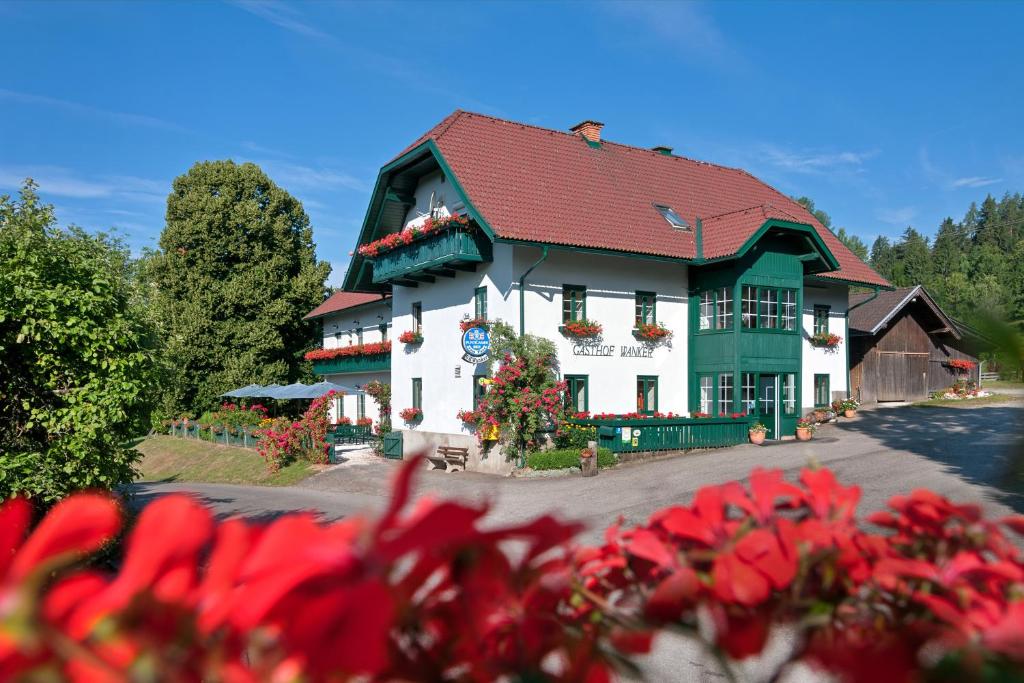 un edificio con fiori rossi di fronte di Biogasthaus Wanker a Techelsberg am Worthersee