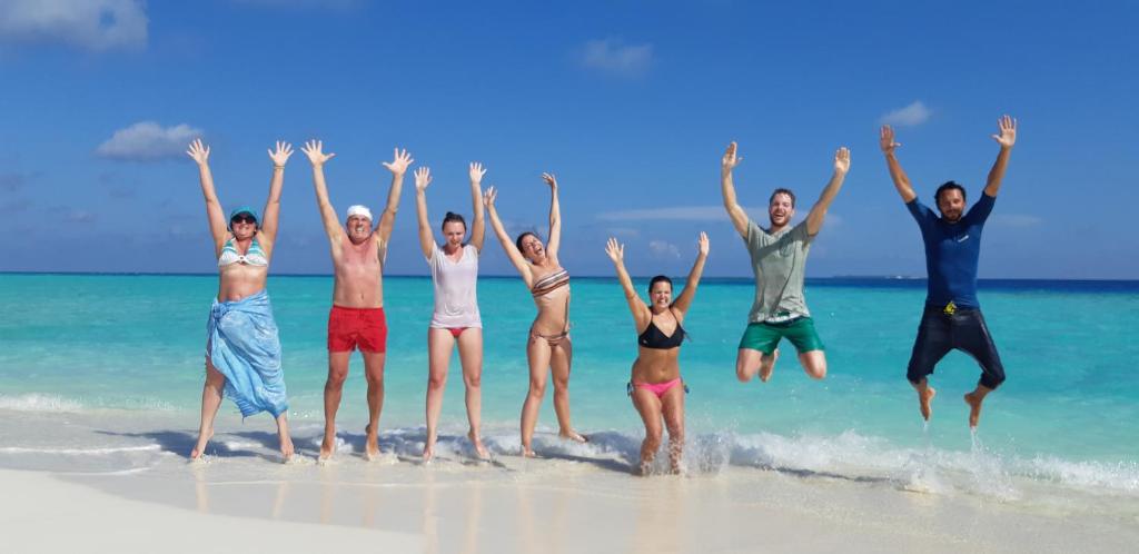 eine Gruppe von Leuten, die am Strand ins Wasser springen in der Unterkunft Masfalhi View Inn in Felidhu-Atoll