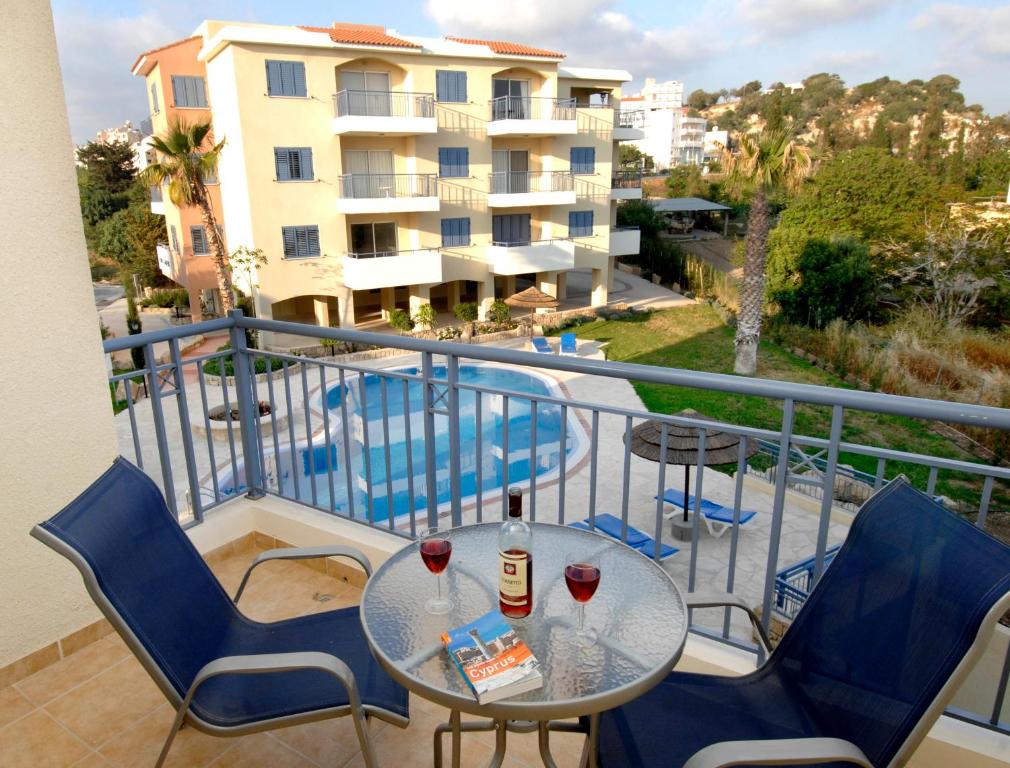 einen Balkon mit einem Tisch und 2 Gläsern Wein in der Unterkunft Hermes Gardens in Paphos City