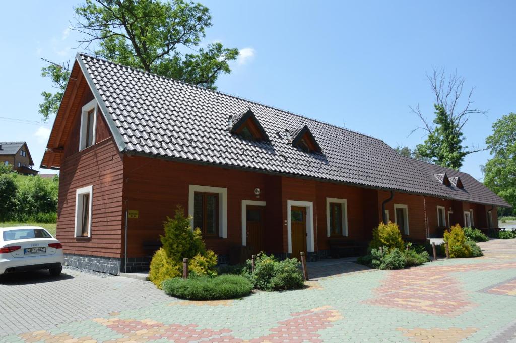 ein braunes Haus mit einem davor geparkt in der Unterkunft Apartmány Divoký Anděl in Dolní Moravice