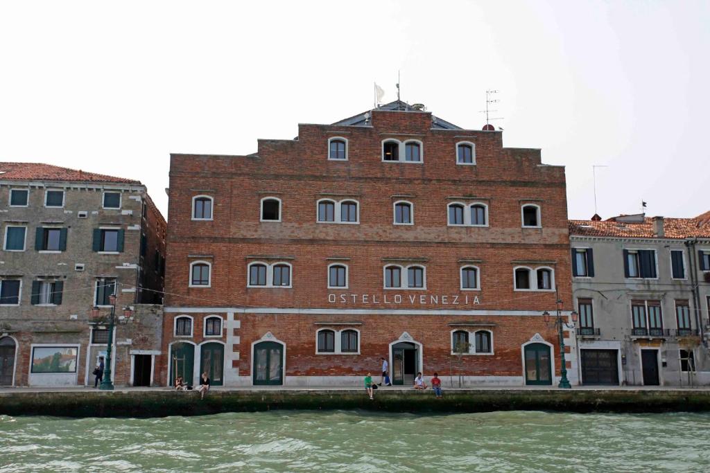 un grand bâtiment en brique à côté d'une masse d'eau dans l'établissement Generator Venice, à Venise