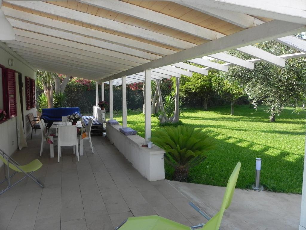 un patio con pergolato bianco, tavolo e sedie di L'ULIVO Marzamemi a Noto