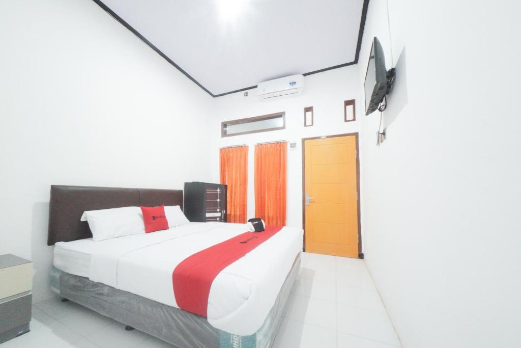 um quarto com uma cama e um relógio na parede em RedDoorz Syariah near Mall Roxy Banyuwangi 2 em Banyuwangi