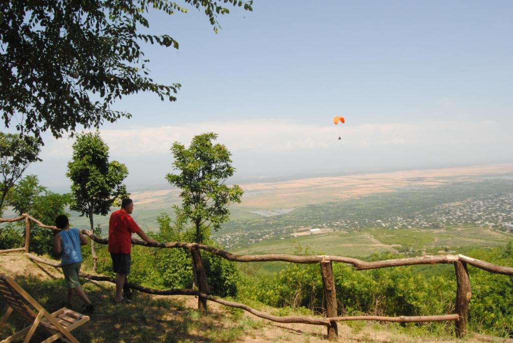deux personnes debout sur une colline en train de regarder un cerf-volant dans le ciel dans l'établissement Tsanava's cottage in Sighnaghi, à Sighnaghi