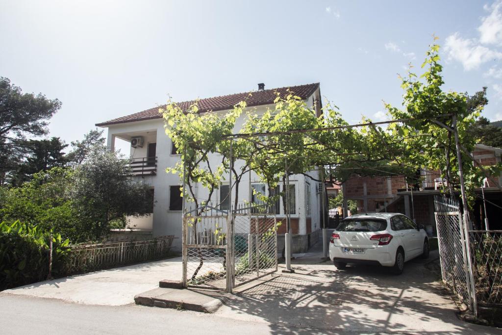 ein weißes Auto, das vor einem Haus parkt in der Unterkunft Stojkovic Family Apartments in Tivat