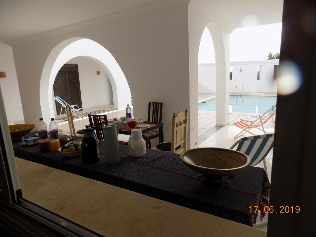 Sīdī ash Shammākh的住宿－Dar Mamina，厨房以及带桌子和游泳池的用餐室。