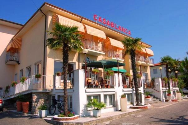 un grand bâtiment avec des palmiers devant lui dans l'établissement Hotel Casablanca, à Lazise