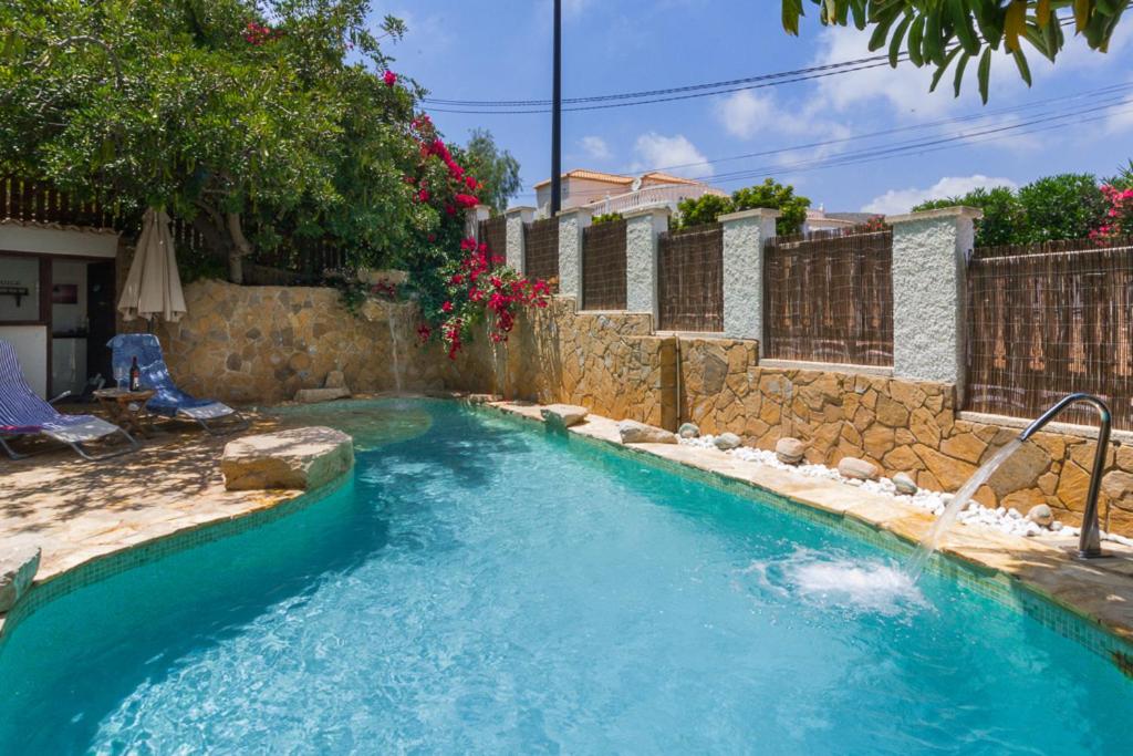 einen Pool in einem Garten mit einer Steinmauer in der Unterkunft Bright villa with salt water pool in El Campello