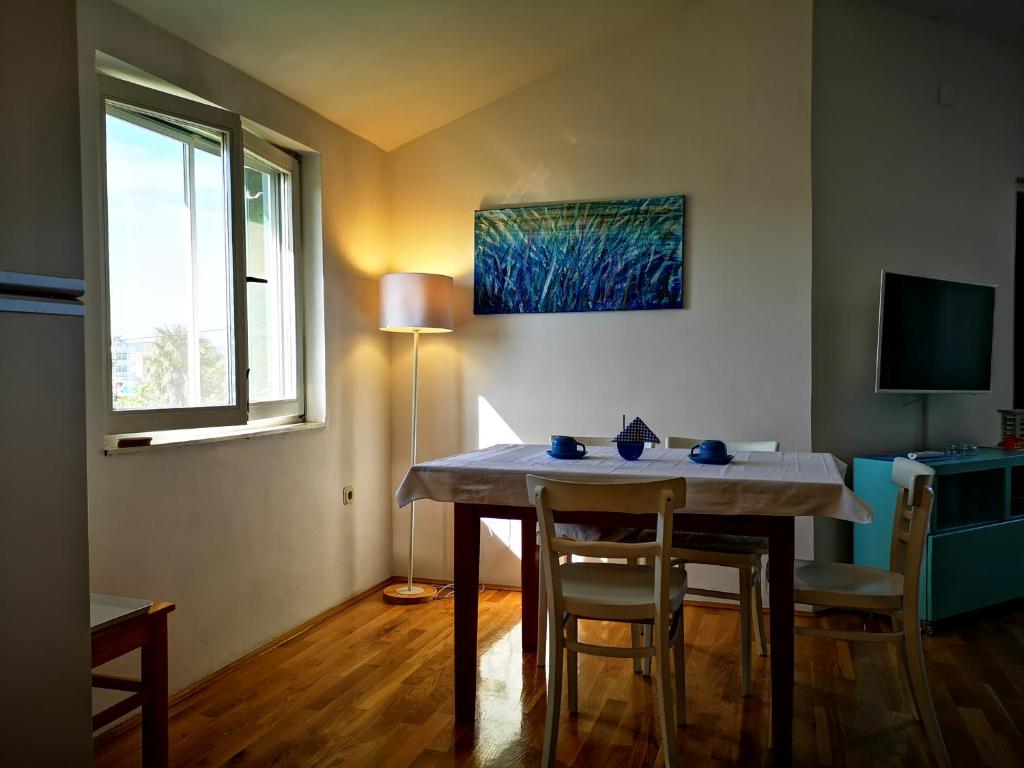 uma sala de jantar com uma mesa e cadeiras e uma janela em Apartmani Labud em Sukošan