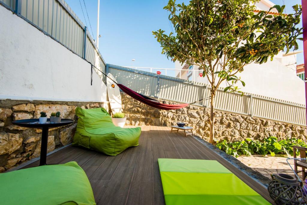 a balcony with green cushions and a hammock at Hostel & Surfcamp 55 in Ericeira