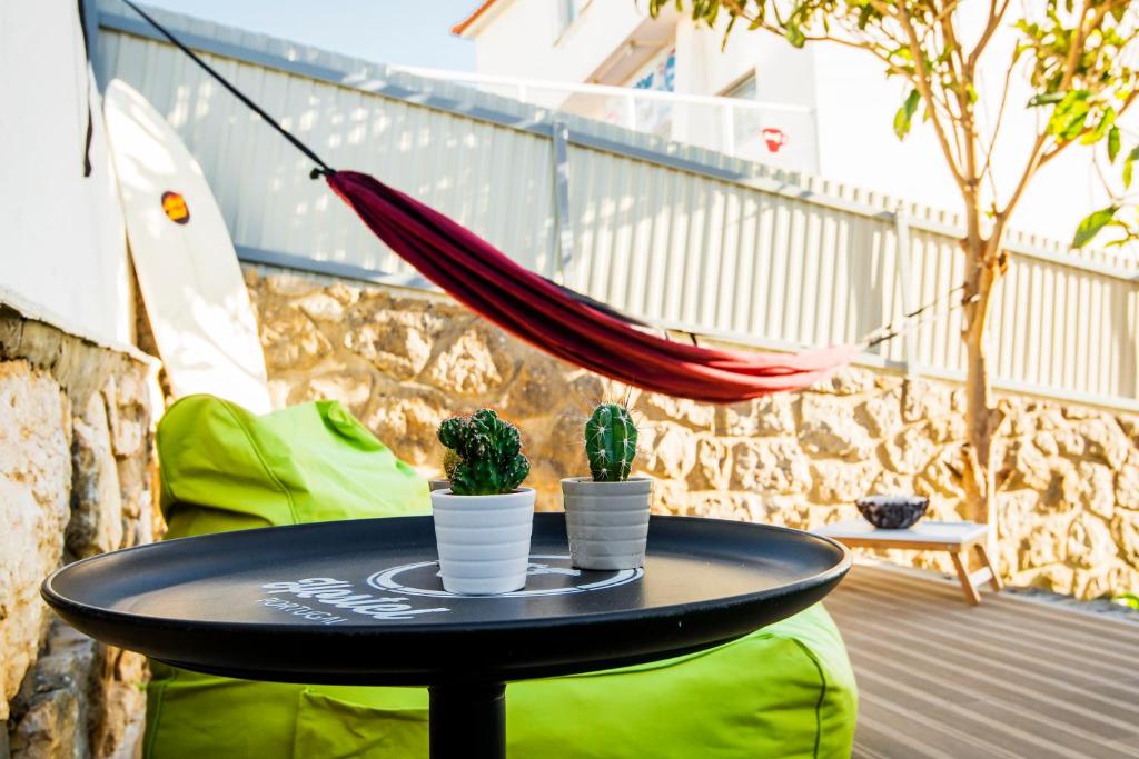 a black table with two cactuses on a balcony at Hostel & Surfcamp 55 in Ericeira