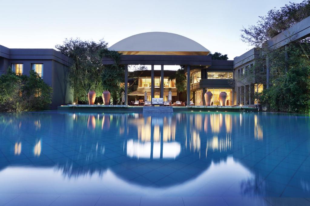a building with a swimming pool in front of a building at Saxon Hotel, Villas & Spa in Johannesburg