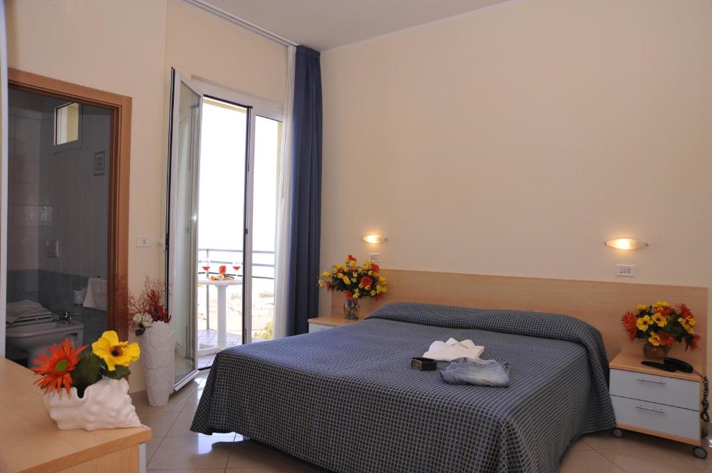 リミニにあるHotel Fantasyのベッドルーム1室(ベッド1台付)、花の咲く大きな窓が備わります。