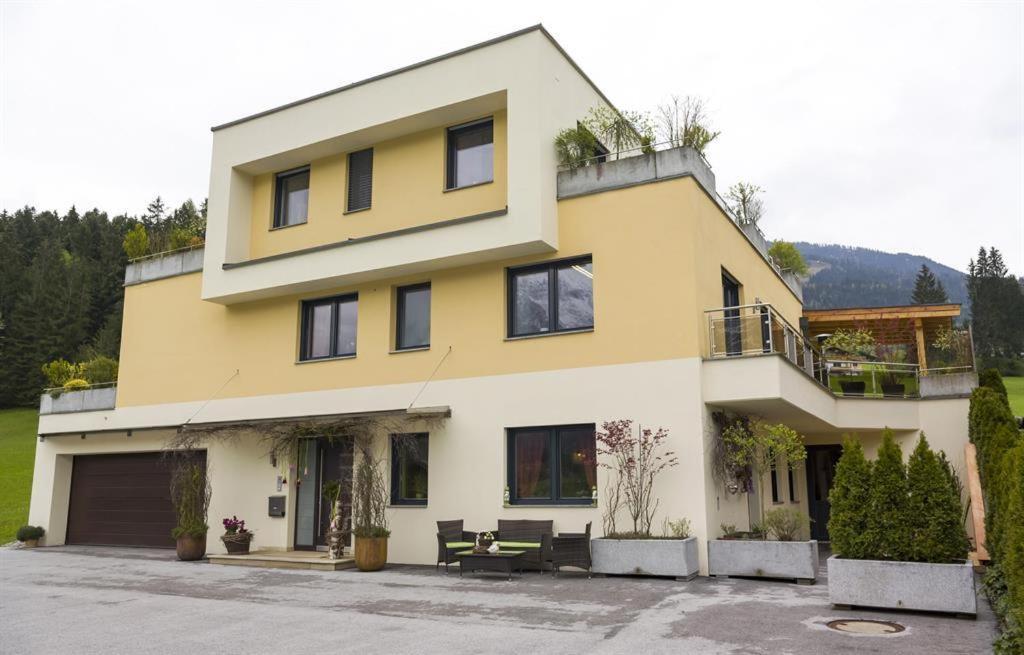 żółto-biały dom z mnóstwem okien w obiekcie Appartement Hoschek w mieście Scheffau am Wilden Kaiser