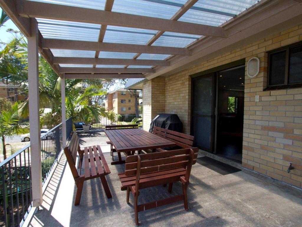 una mesa de madera y bancos en un patio en Sandcastle 7 with WiFi, en Tuncurry