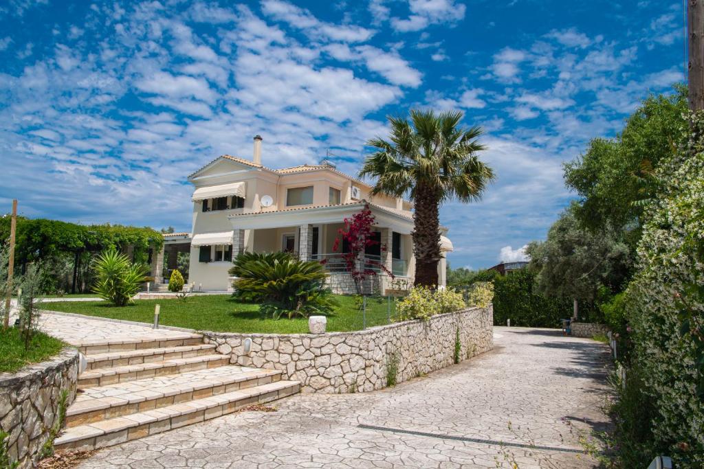 a white house with a palm tree and a stone wall at Violet Luxury Villa in Lefkada Town