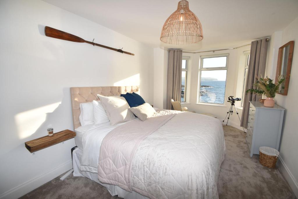 a bedroom with a white bed with a view of the ocean at The Promenade, Portstewart in Portstewart