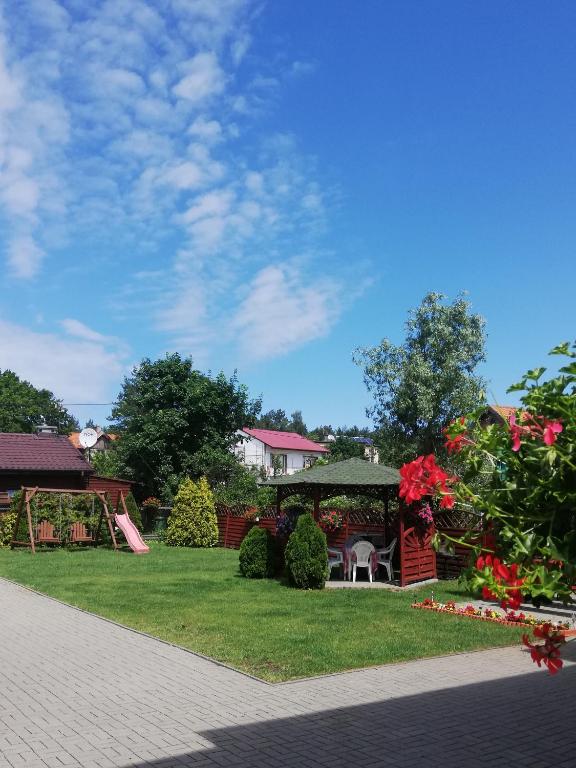 a garden with a gazebo and flowers on the grass at Pokoje Gościnne Słoneczko in Kąty Rybackie