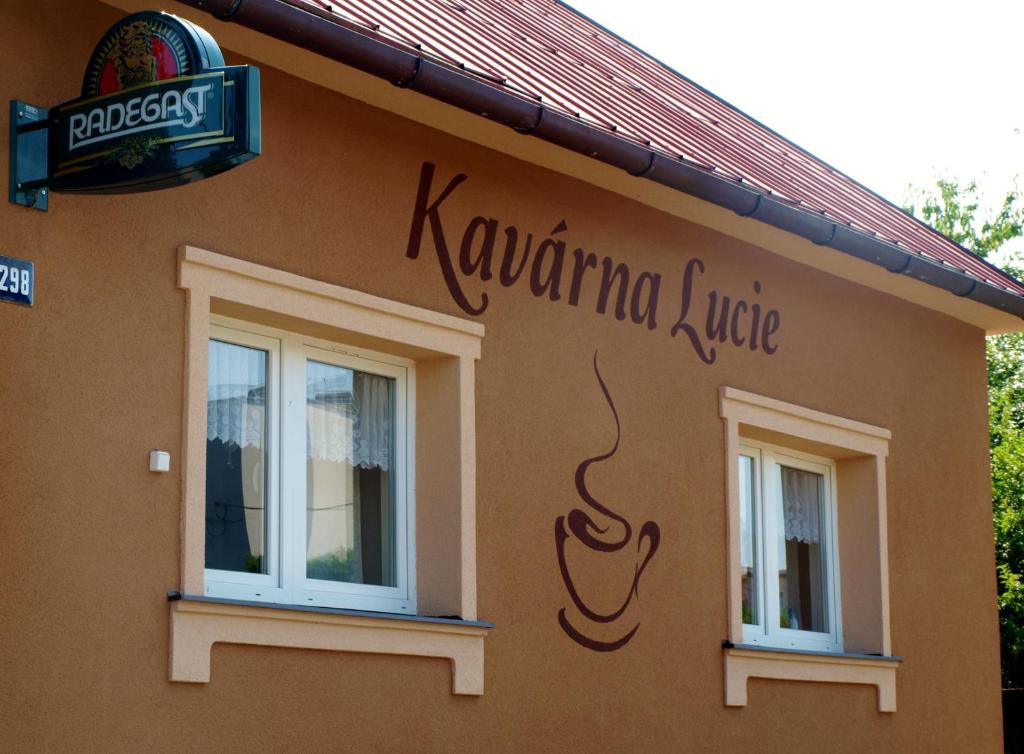 una señal en el lateral de un edificio con dos ventanas en Kavárna Lucie s ubytováním en Horní Těrlicko