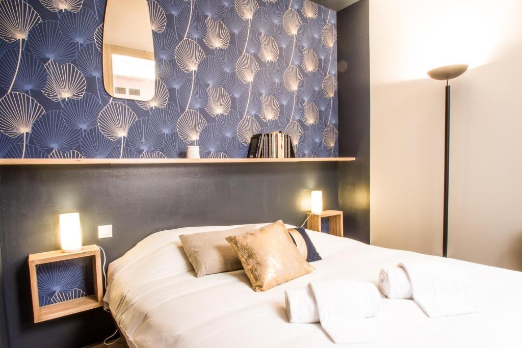 - une chambre avec un grand lit blanc et un mur bleu dans l'établissement L'Opera by Cocoonr, à Toulouse