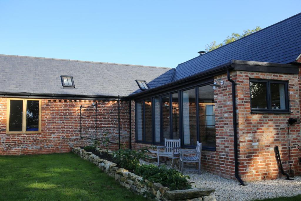 een stenen huis met een stoel in de tuin bij Hedges House in Buckingham