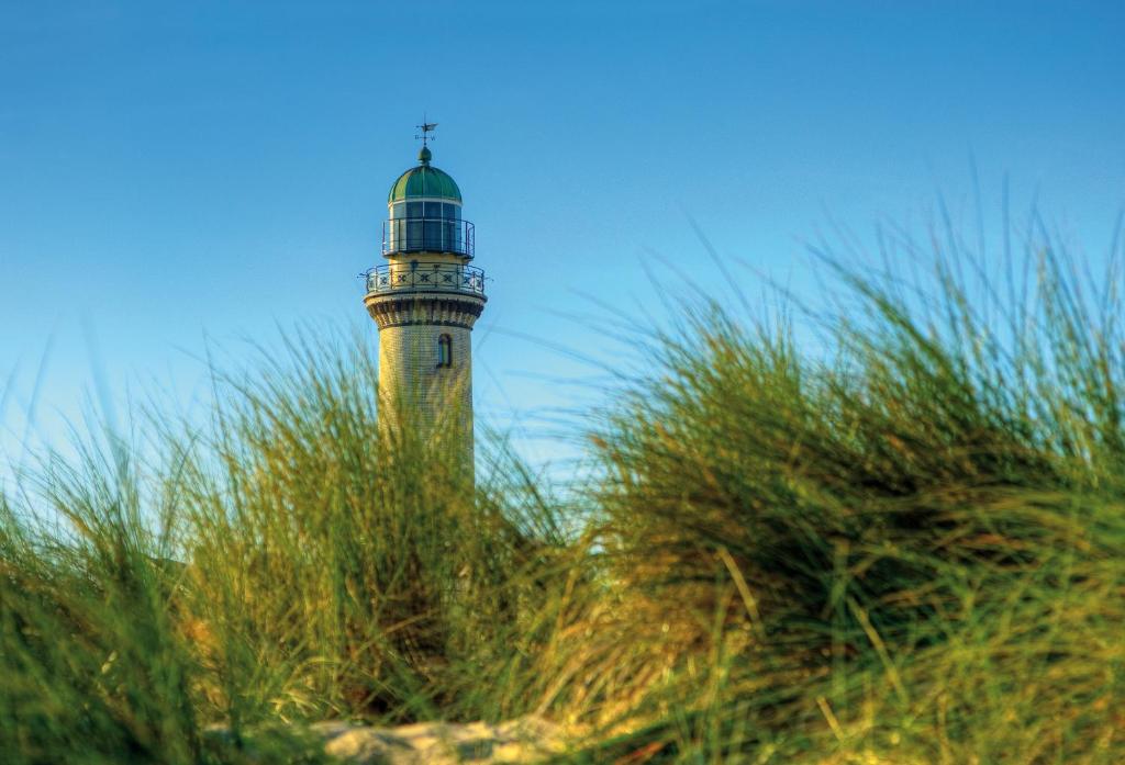 un faro sentado en la cima de una playa junto a la hierba en Ferienwohnung Warnemünde, en Warnemünde