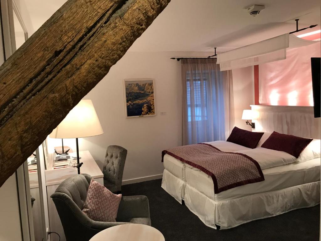 ein Schlafzimmer mit einem Bett und einem Stuhl in der Unterkunft Altes Amtshaus, 3-Sterne Hotel Garni Superior in Mulfingen-Ailringen